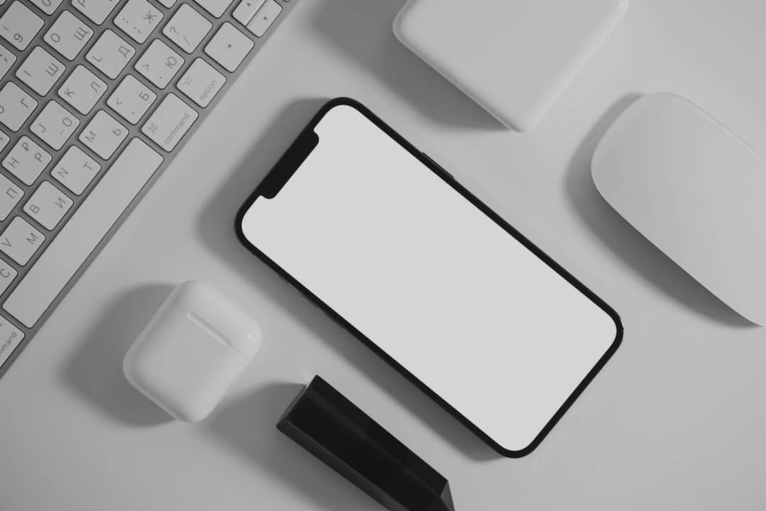 Modern workspace setup with smartphone, wireless earbuds, keyboard, and mouse, illustrating tech integration for productivity in work pods and booths.