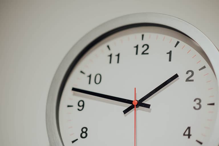 Analog wall clock showing close-up of hands at 2:10, representing time management in remote work and mastering timezones.